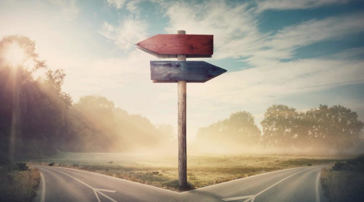 Surreal landscape with a split road and signpost arrows showing two different courses, left and right direction to choose. Road splits in distinct direction ways. Difficult decision, choice concept.